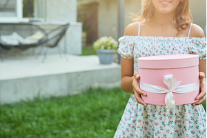 Young girl holds gift box in garden
