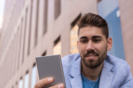 Handsome young man smiling when he is using his mobile phone, a Person Photo by RF Images