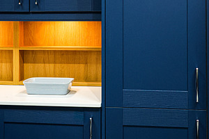 Blue kitchen cabinets featuring integrated storage solutions, wood shelves with, a Photo by Studio ANNA
