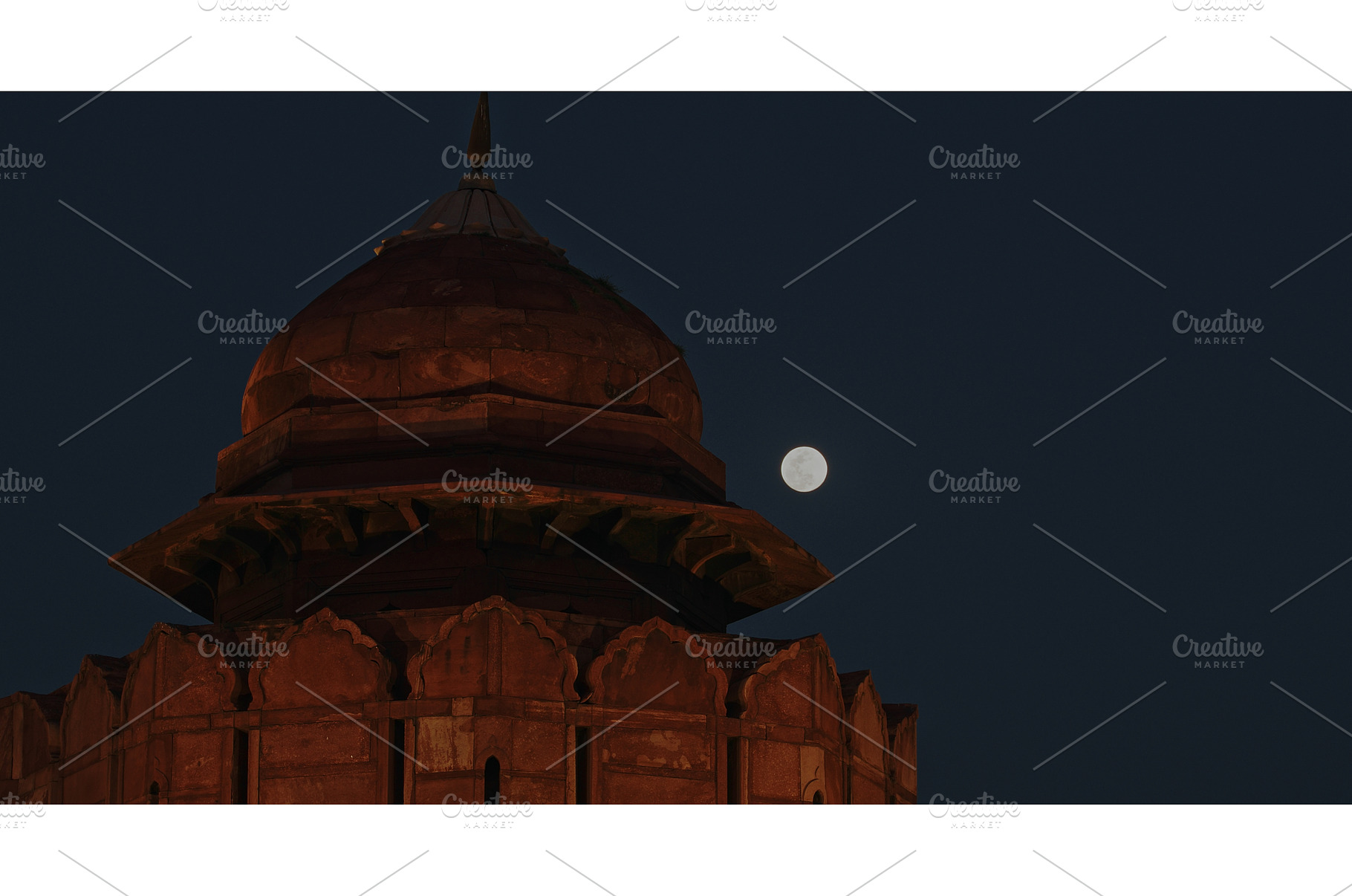 Full moon rising behind illuminated, an Architecture Photo by Our Amazing World