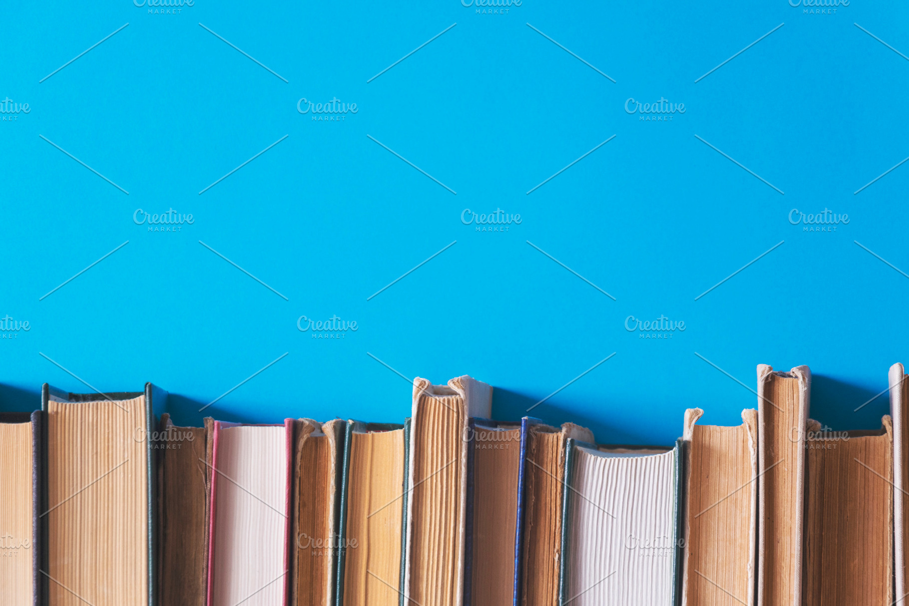 Old books on a blue background, a Business Photo by Ti-Di