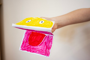 Hand holding colorful paper craft of face with expressive design, a Photo by AS photostudio