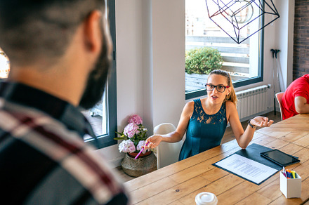 Happy woman talking with unrecognizable man in coworking office, a Business Photo by davidpereiras