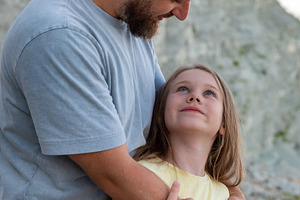 Happy father hugging his daughter on a rocky outdoor landscape with a cliff bac, a Person Photo by Ales Munt