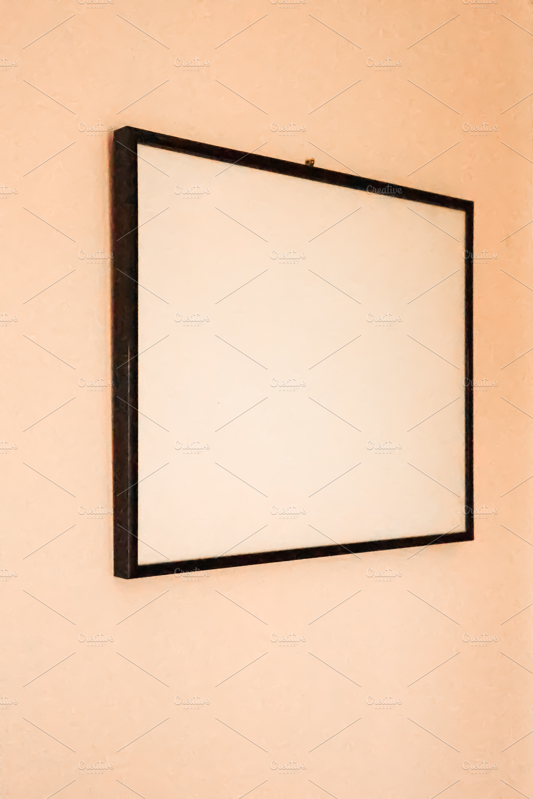 Blank picture frame on peach wall offering copy space for mockups, interior des, a Photo by Studio ANNA