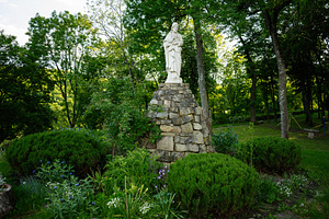 Marble statue of Jesus Christ in a peaceful garden surrounded by lush green tre, a Photo by AS photostudio