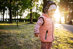 Young child enjoying a sunny day in a park with green trees, a Photo by AS photostudio