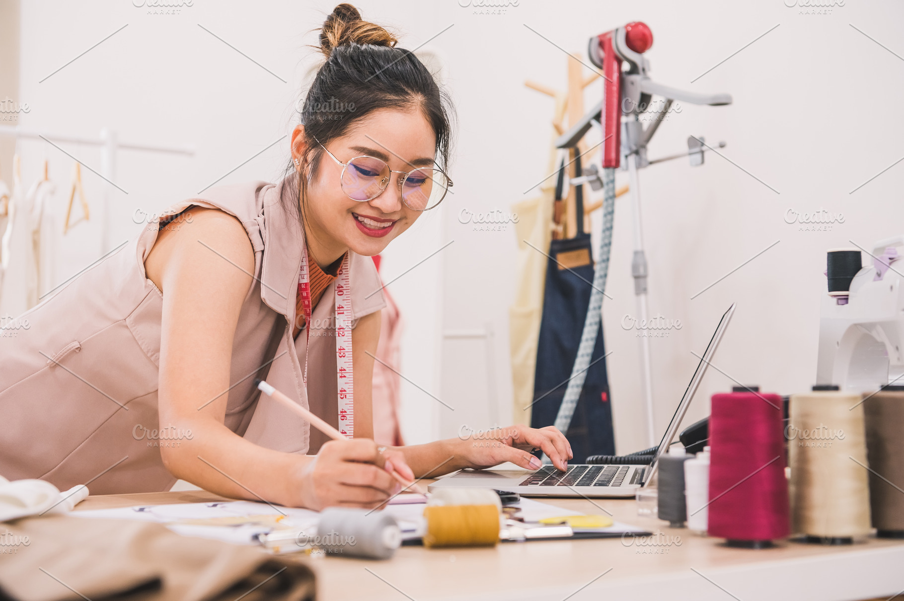 Attractive Asian female fashion designer working in home office, a Person Photo by Ministocker
