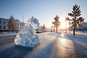 Large ice sculpture of a bear in a winter park at sunset, a Photo by AlyaAnd