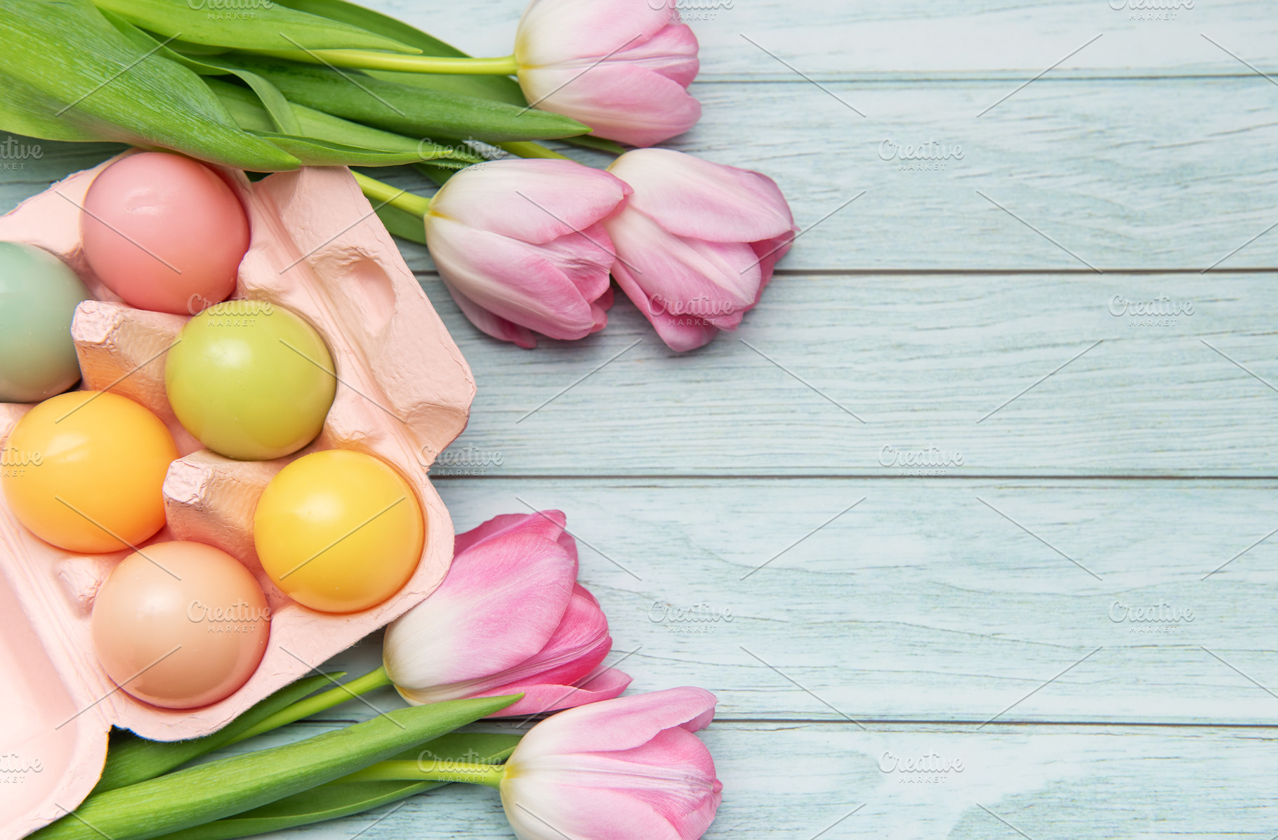 Pastel colored easter eggs and pink tulips creating festive bord, a Holiday Photo by Olena Rudo