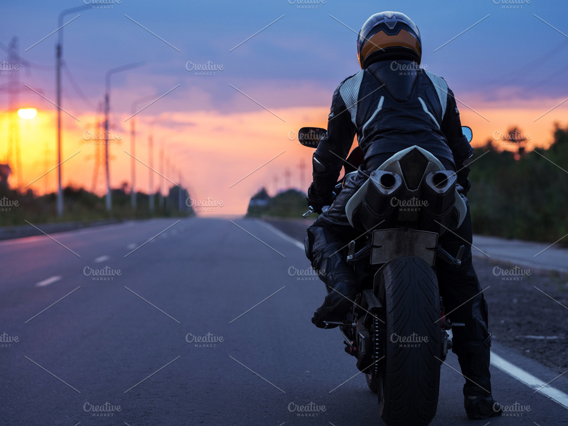 motorcyclist stands on an empty road at sunset , back view , copy space. Travel, a Photo by PavelKant