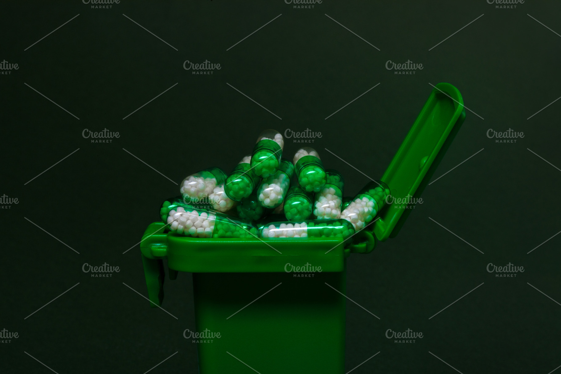 Overflowing green medical waste bin filled with white and green capsules agains, a Health & Medical Photo by Ales Munt