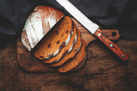 Sourdough rye bread with raisins, pieces on wooden cutting board, a Food & Drink Photo by 5PH