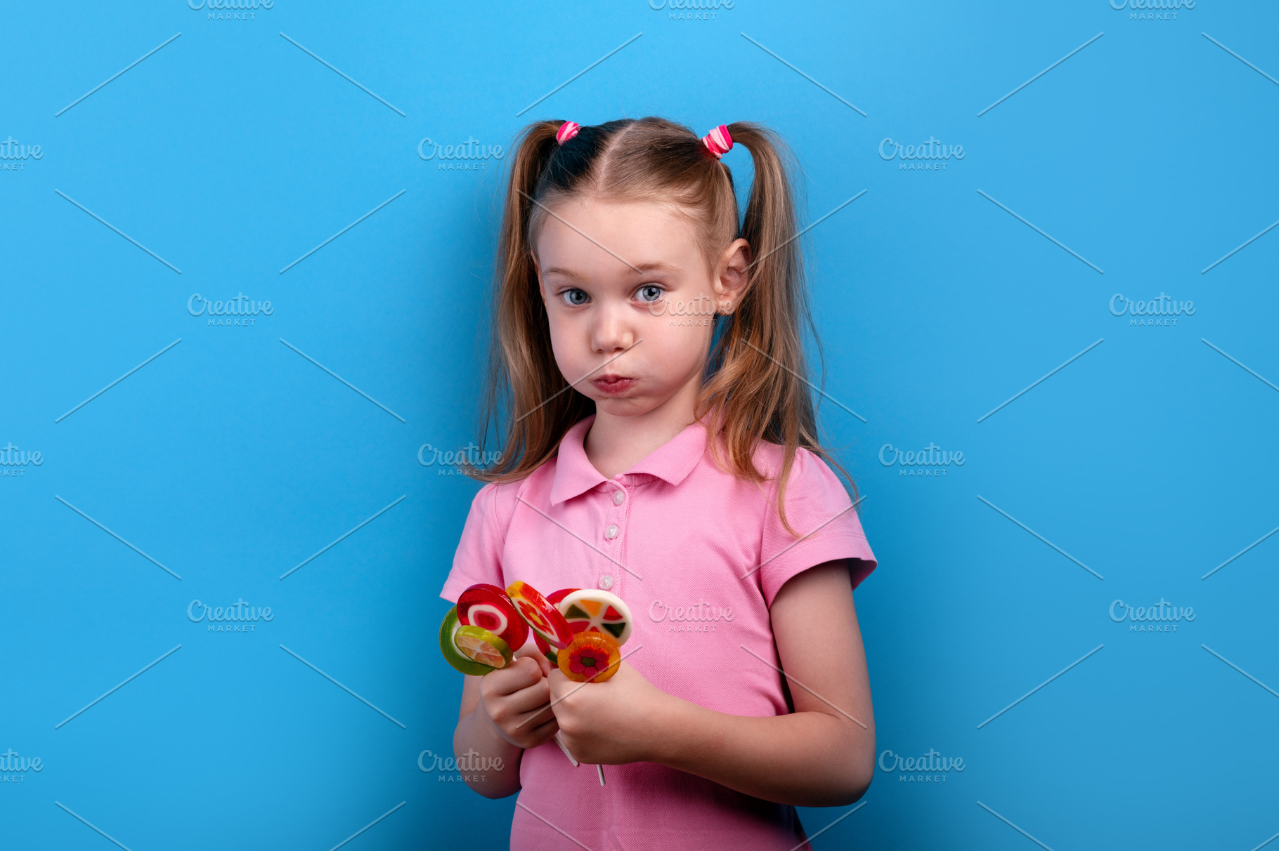 Cute girl in a pink shirt puffing her cheeks while holding colo, a Person Photo by Ales Munt