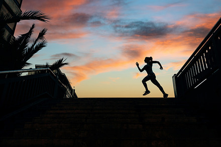Female runner silhouette running over urban background with palm