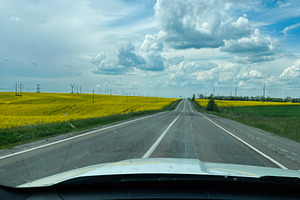 Country road view with a car dashboard foreground and scenic cloudy sky, a Photo by AS photostudio