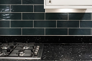 Modern kitchen interior, dark green subway tile, black granite countertop, whit, a Photo by Studio ANNA
