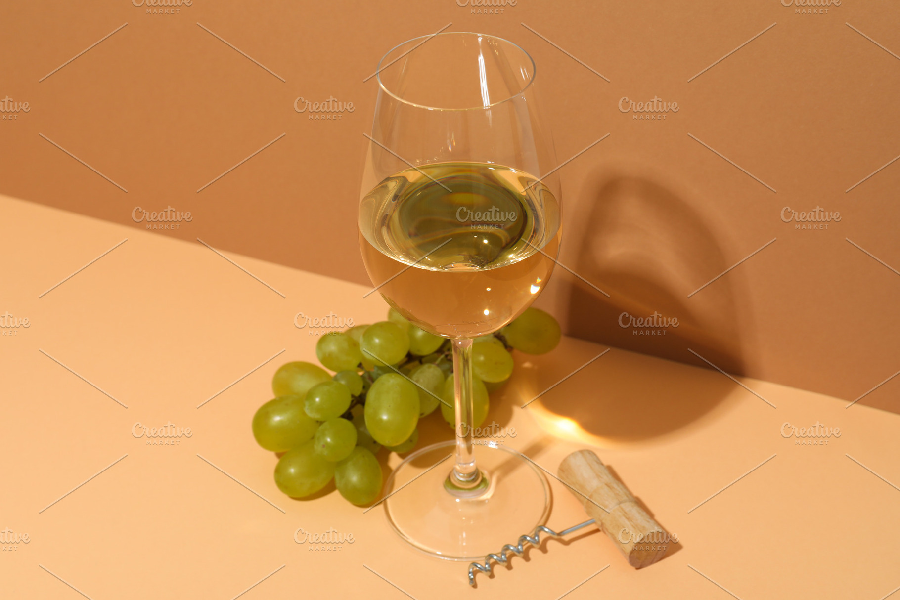 Glass of wine, corkscrew and grape on beige and light brown back, a Food & Drink Photo by AtlasStudio PRO