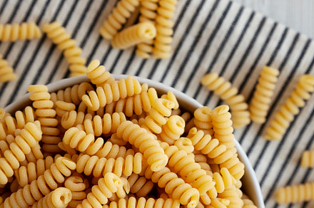 Uncooked Organic Dry Fusilli Pasta in a Bowl, top view. Flat lay, a Food & Drink Photo by LiudmylaChuhunova