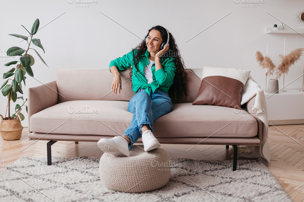 Cheerful Arabic Woman Enjoying Listening To Music Wearing Headphones Indoor, a Photo by Prostock-Studio (Photo 1 of 2)