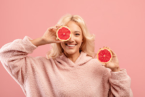 Vitamins for beauty and skin care. Happy caucasian lady posing with grapefruit, a Photo by Prostock-Studio