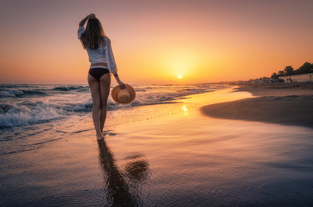 Beautiful woman with straw hat is standing in sea with waves, a Person Photo by den-belitsky
