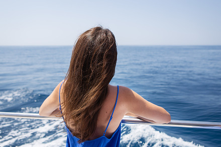 Young beautiful brunette girl sits with her back on a yacht against the backdro, a Person Photo by Artsaba Family