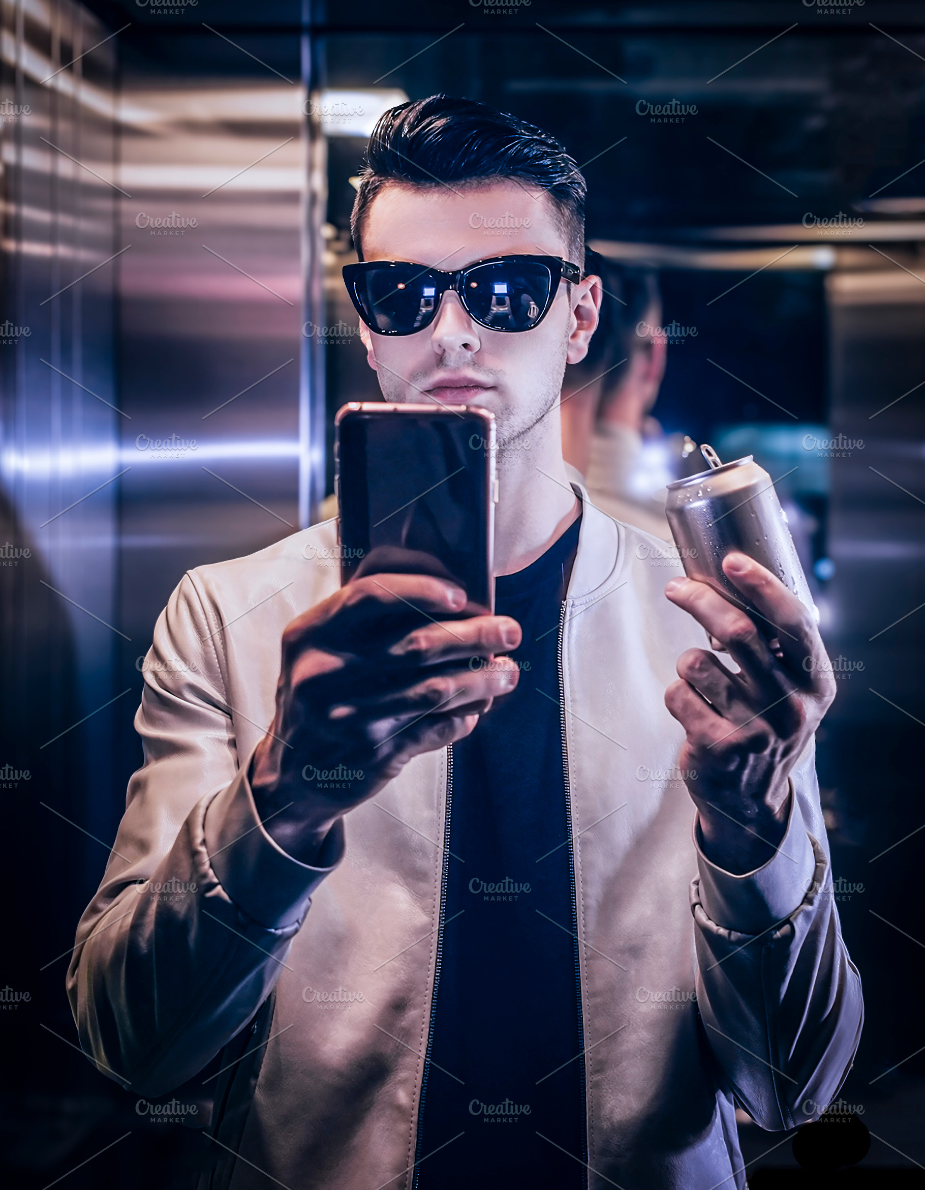 Man on an elevator taking a selfie and holding a metallic soda c, a Person Photo by DanFLCreativo