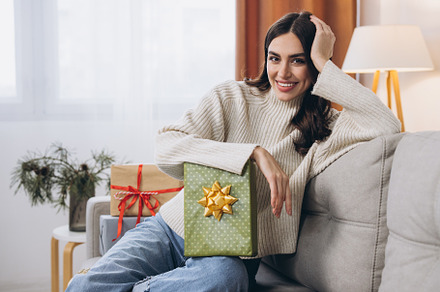 Beautiful happy woman unwrapping New Year or Christmas presents