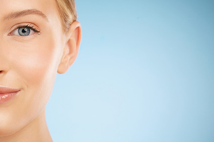 Skincare, smile and half portrait of a woman for dermatology isolated on a blue background. Makeup, wellness and face of a model for cosmetics, health and collagen with mockup space on a backdrop, a Photo by Peopleimages.com