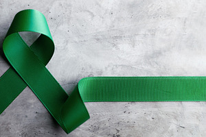 Mental Health Awareness Concept. Green Ribbon lay on Grey backgr, a Photo by salmon.black
