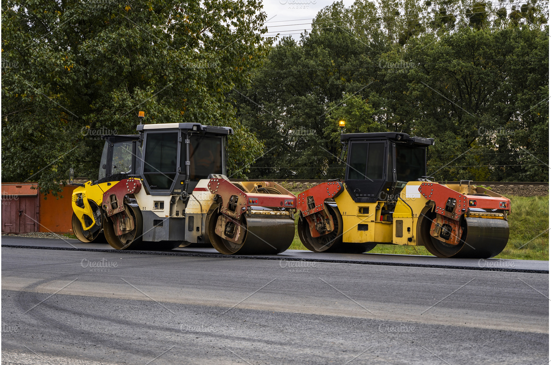 Two road rollers parked on highway, an Industrial Photo by volodymyrshtun13795