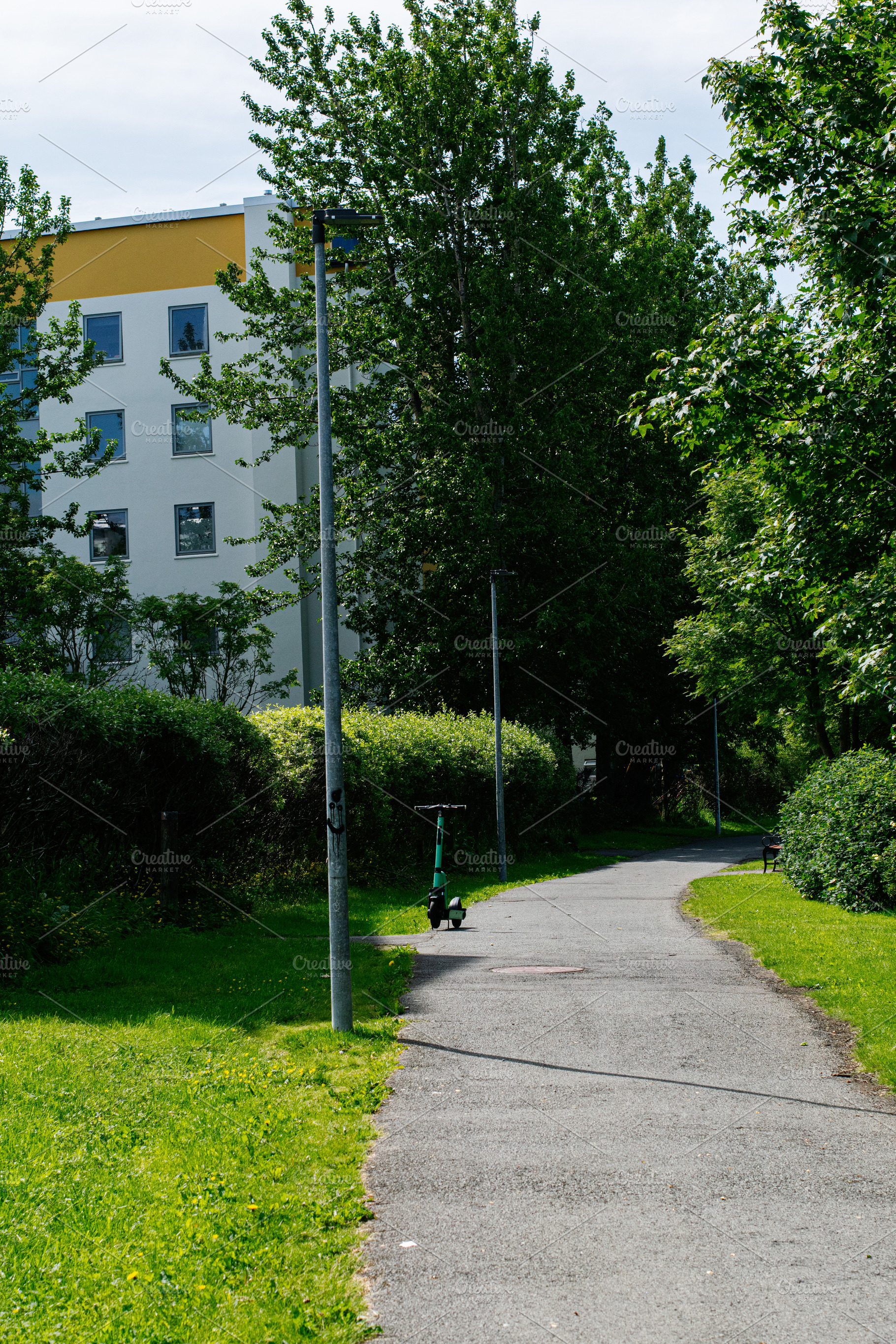 Pathway with trees and parked electric scooter in Reykjavik, Iceland, a Photo by AS photostudio