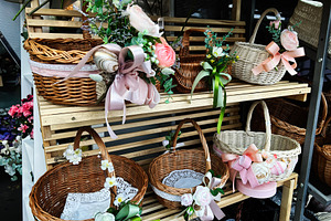 Decorative wicker baskets with floral and ribbon adornments displayed on wooden, a Photo by AS photostudio