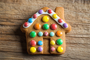Christmas gingerbread house cookie on wooden background, a Food & Drink Photo by AlyaAnd