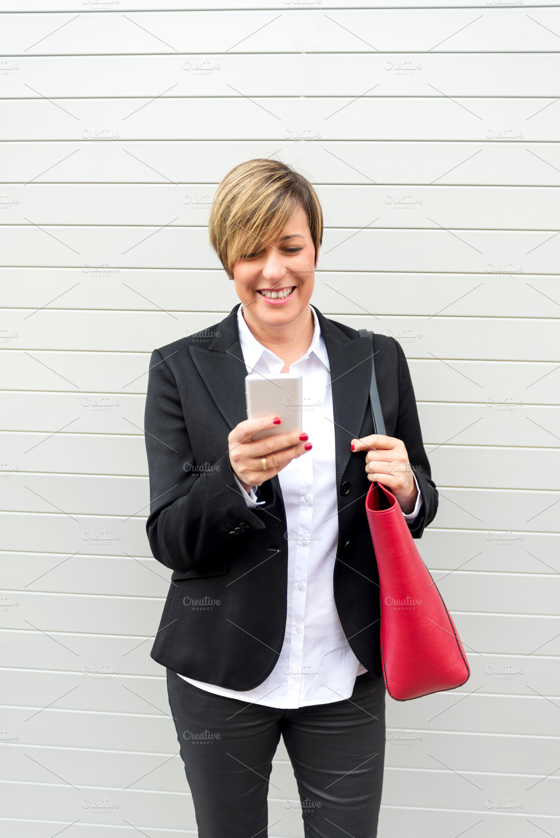 Businesswoman checking smartphone and smiling, a Photo by RF Images