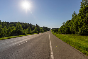 an empty straight paved road against a blue sky background, a Photo by rsoollAI