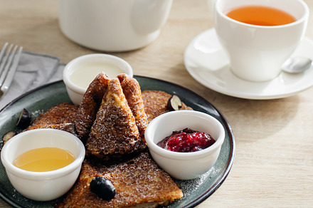 Delicious thin pancakes with jam, honey and sour cream and cup of tea on light, a Food & Drink Photo by Anikona