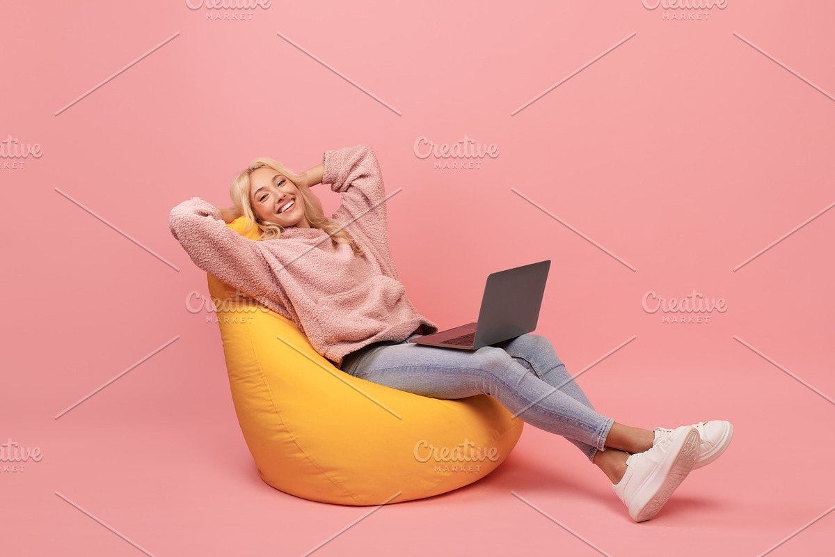 Relaxed freelancer lady leaning back in beanbag chair, resting while working on, a Photo by Prostock-Studio (Photo 2 of 2)