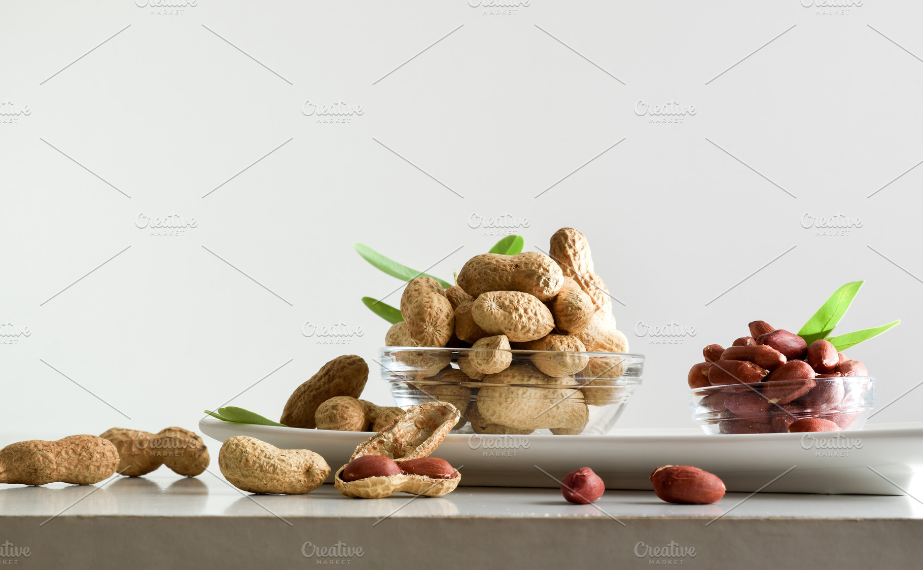 Peeled and unpeeled peanuts in glass bowls isolated on plate, a Food & Drink Photo by Davizro's Market
