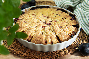Baked plum dessert with crumb topping on rustic table, a Food & Drink Photo by Olena Rudo