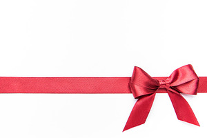 Red ribbon and bow creating festive border on white, a Holiday Photo by Olena Rudo