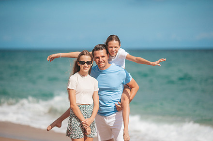 Portrait of father with his adorable daughters on the beach during their summer, a Person Photo by travnikovstudio