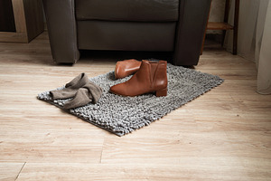 Pair of brown leather ankle boots on rug in cozy living room, an Industrial Photo by MDBildes