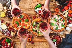 Pizza party with friends. Top view people holding glasses with r