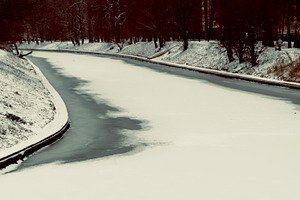 A serene winter scene featuring a snow-covered riverbank, with a winding river, an Industrial Photo by Textures & Backgrounds