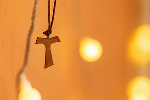 Tau cross hanging from a leather cord on a blurred background wi, a Photo by Antonio Gravante Market