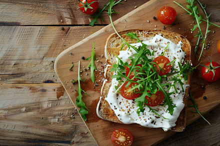 Sandwich with cream cheese, microgreens and tomatoes on wooden table, a Food & Drink Photo by AlyaAnd