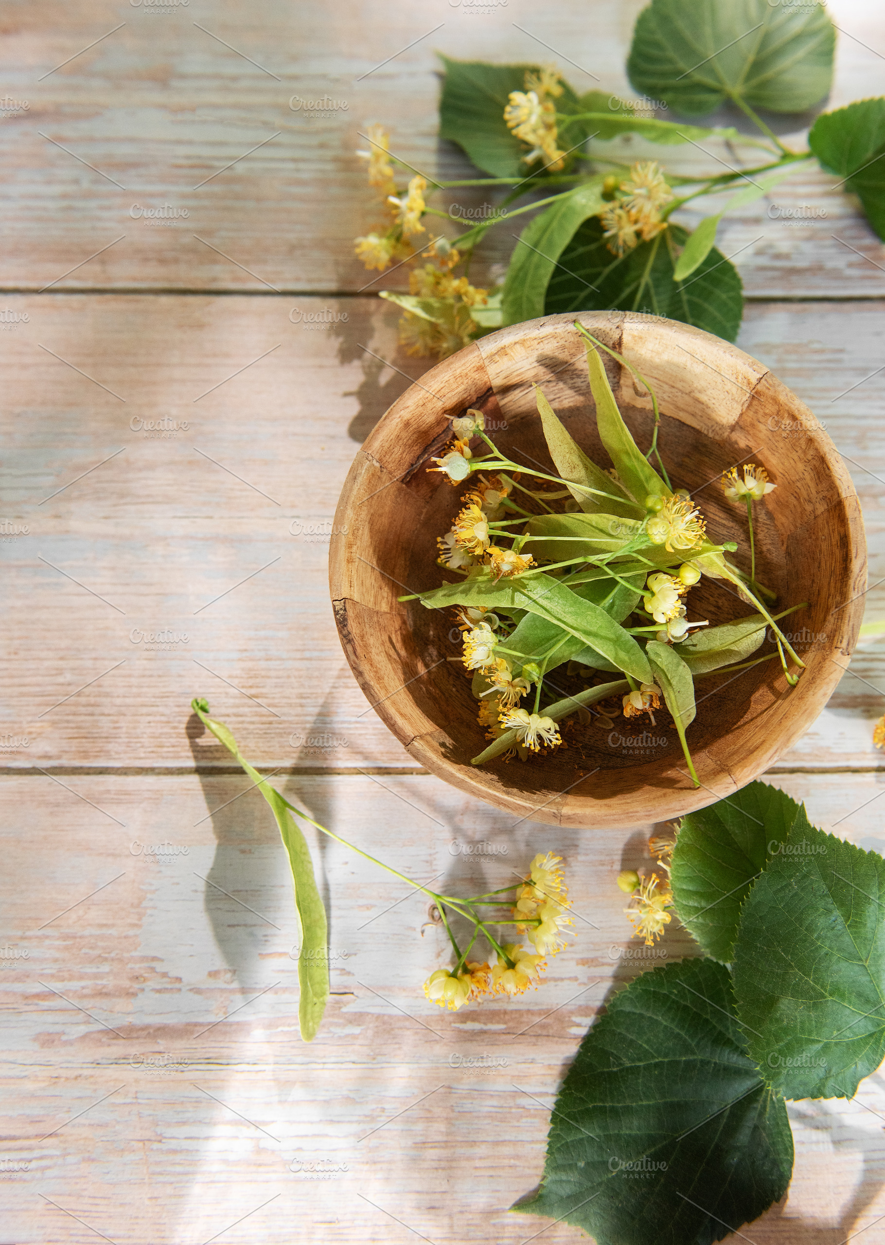 Linden flowers in wooden bowl on light wood, a Food & Drink Photo by Olena Rudo