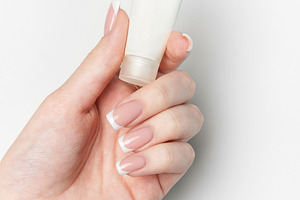Woman hand holding white cosmetic tube on white background, a Beauty & Fashion Photo by Olena Rudo